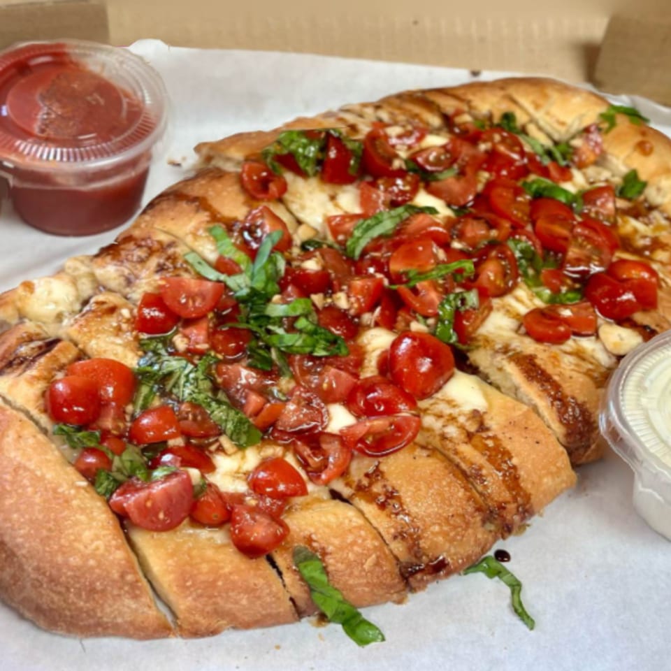 Pioneer Pizza's bruschetta bread, topped with diced tomatoes, fresh basil, and balsamic glaze.