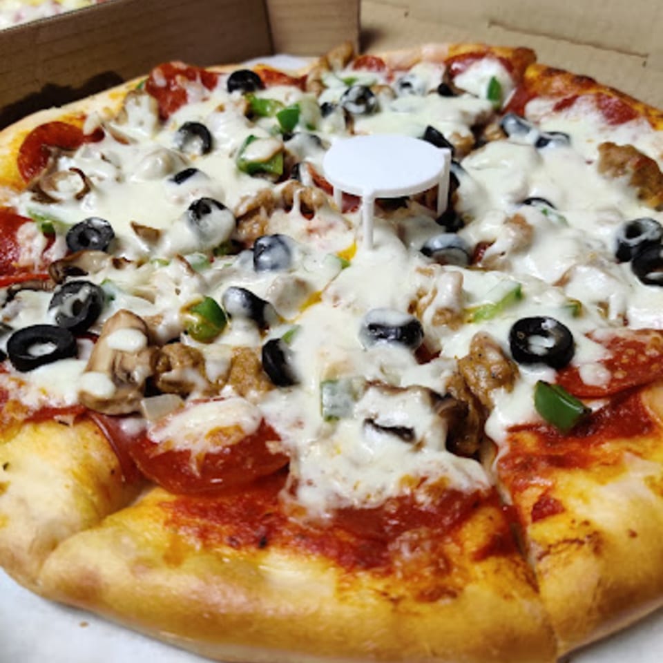 Pioneer Pizza's whole pizza with pepperoni, olives, mushrooms, and green peppers in a box.